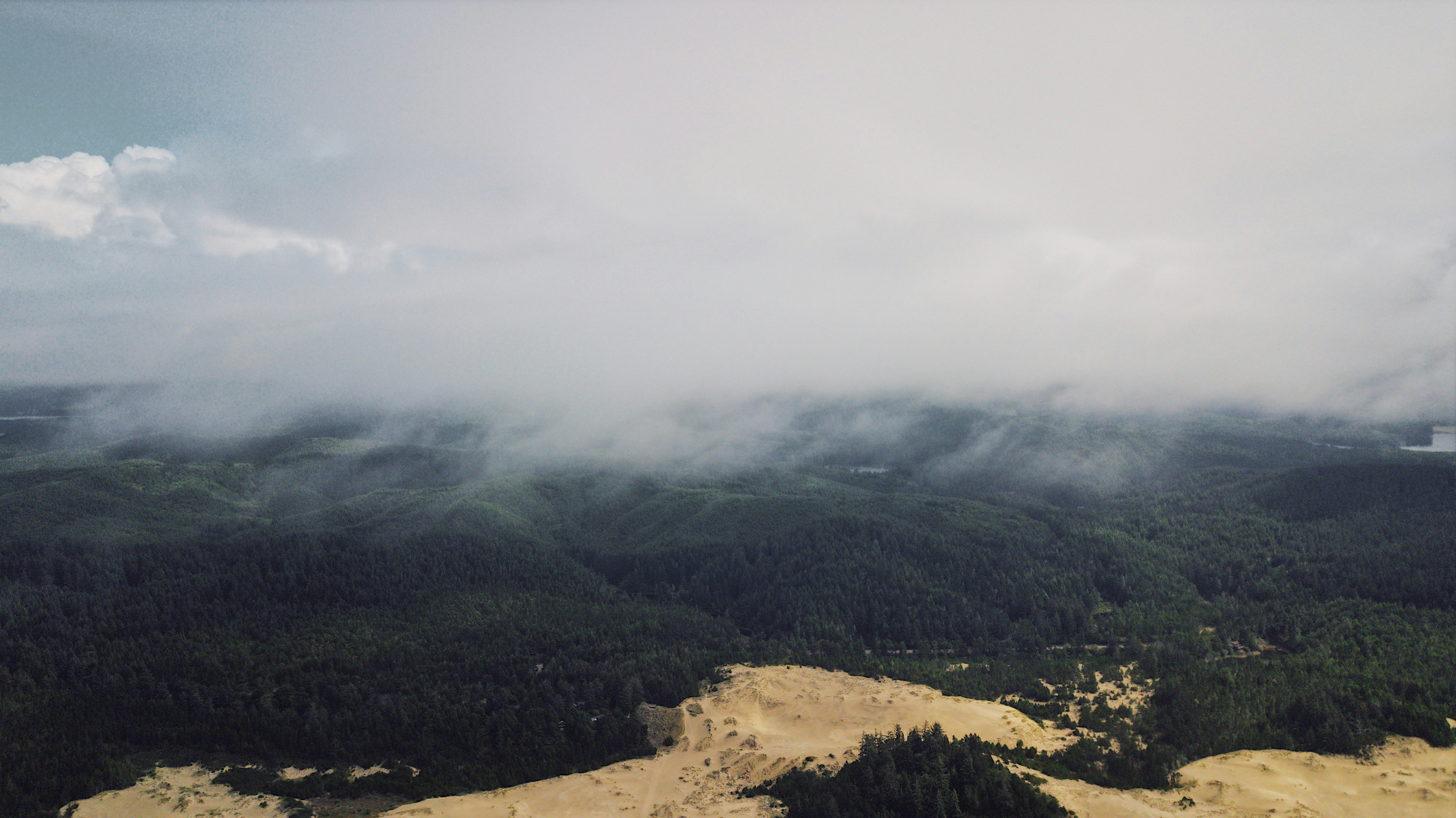 an aerial view of a mountain range with clouds in the sky