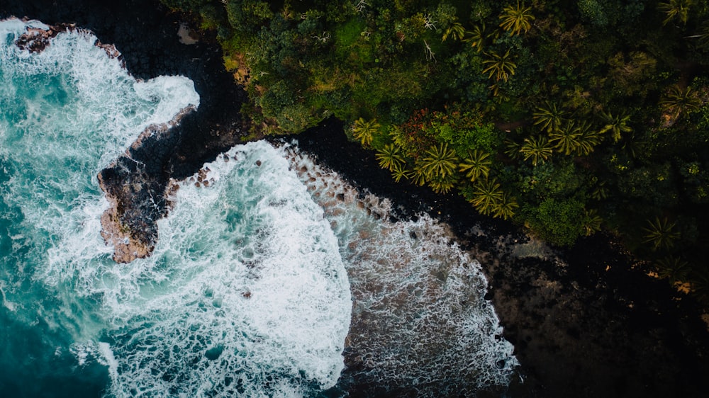an aerial view of the ocean with waves crashing on the rocks