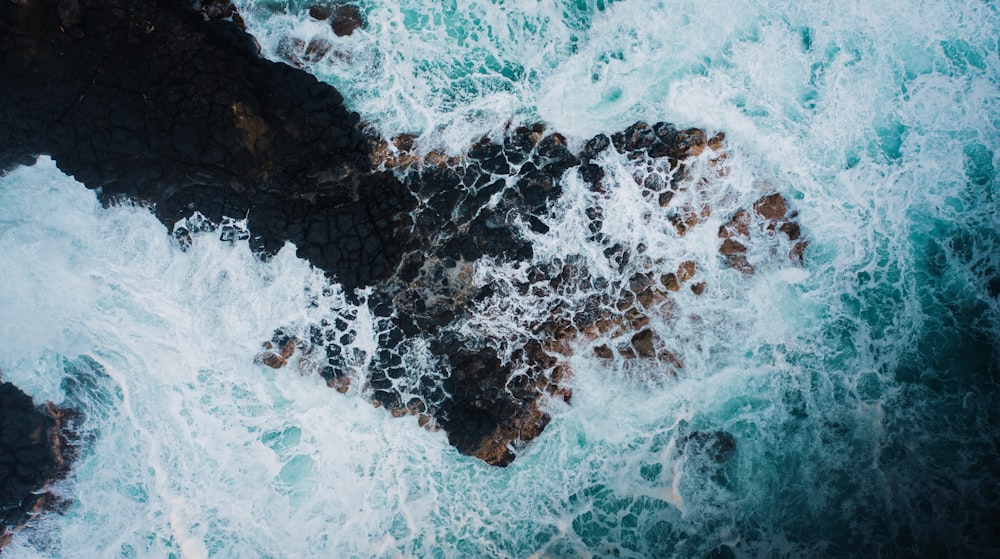 an aerial view of the ocean and rocks