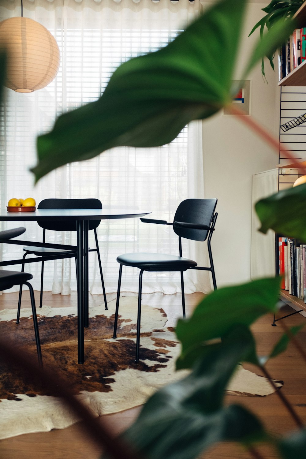 a room with a table, chairs, and bookshelf