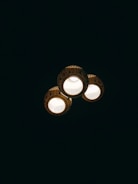 Three ceiling lights with decorative patterns illuminate against a dark background. Each light fixture has intricate detailing around its edges.