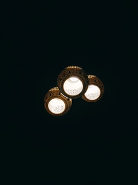 Three ceiling lights with decorative patterns illuminate against a dark background. Each light fixture has intricate detailing around its edges.