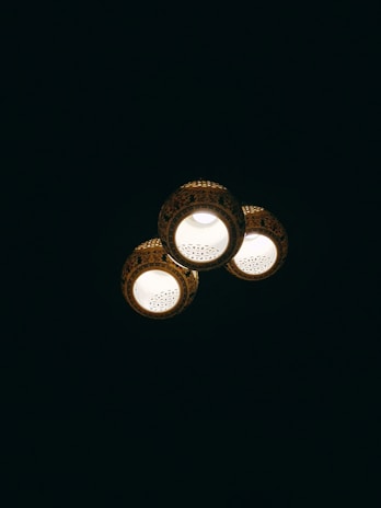 Three ceiling lights with decorative patterns illuminate against a dark background. Each light fixture has intricate detailing around its edges.