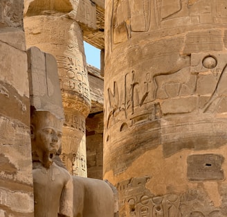 a statue of an egyptian god next to a pillar