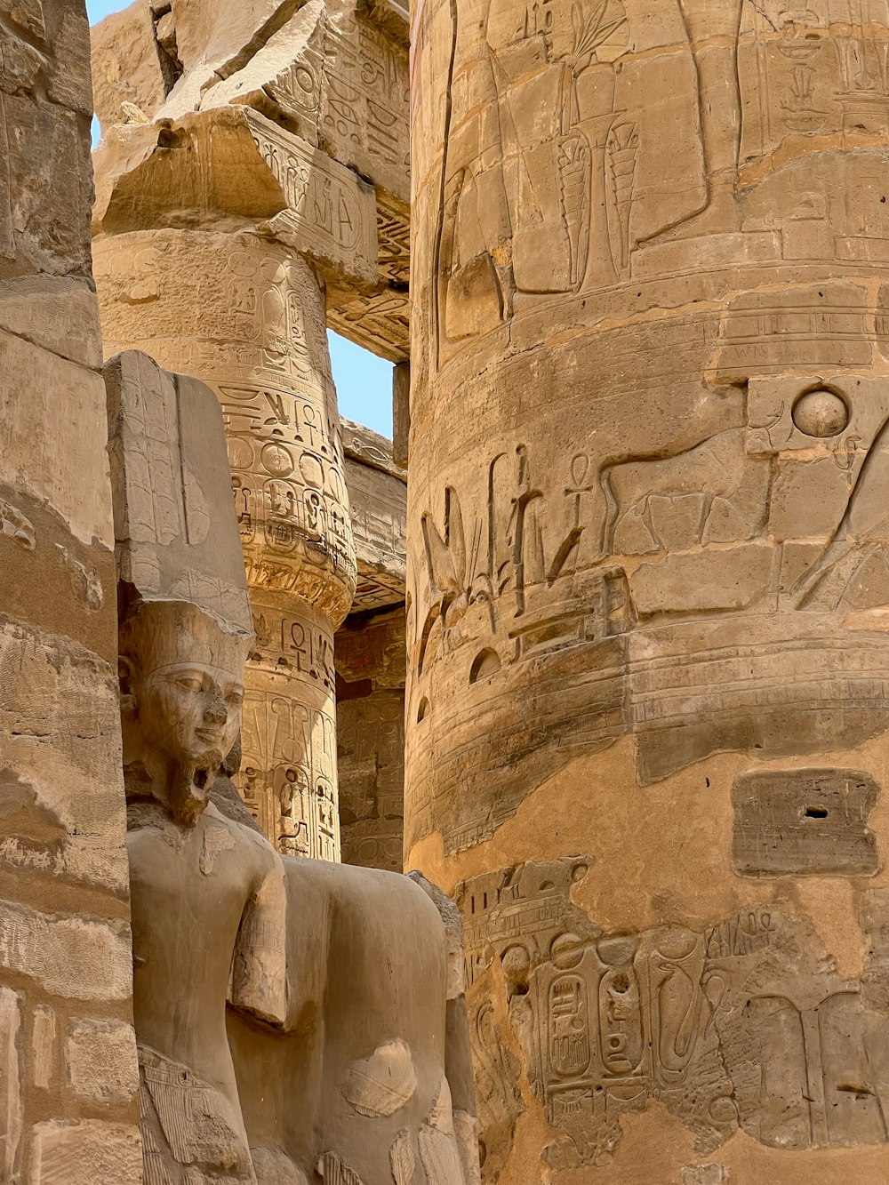 Una estatua de un dios egipcio junto a un pilar