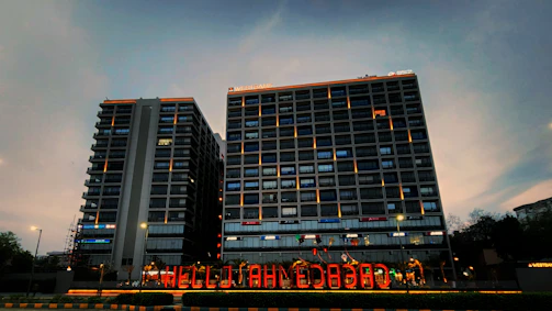 A high-rise building in Bangalore housing Aiyyaar Tech Solutions, glowing warmly at sunset with animated city lights.