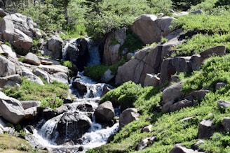 A serene scene of green mountains with a clear waterfall flowing gently