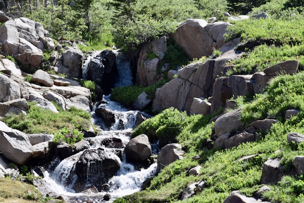 A serene scene of green mountains with a clear waterfall flowing gently