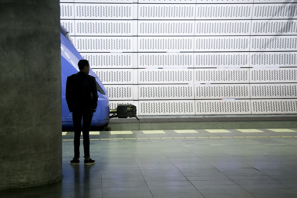 a man standing in front of a blue train