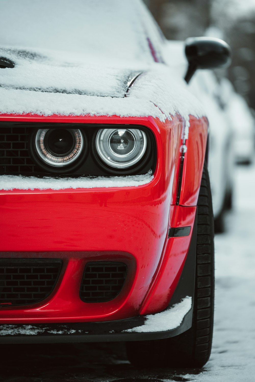 the front of a red car covered in snow