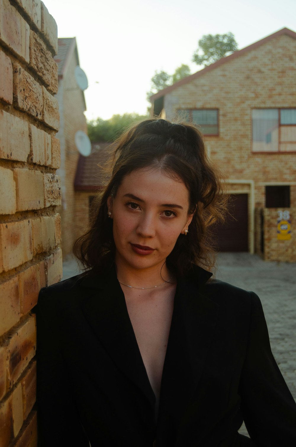 a woman standing next to a brick wall