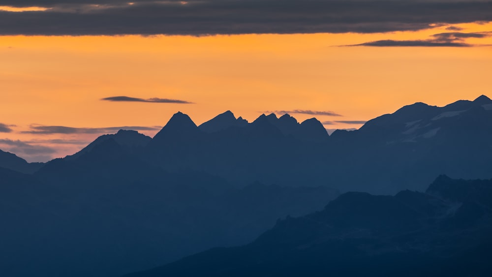 a plane flying over a mountain range at sunset