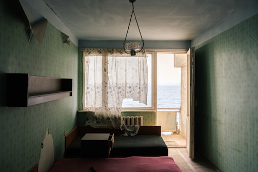 Bright room with sea-inspired decor, soft green accents, and a large window overlooking the Adriatic.