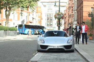 A sleek Silver Raine vehicle waiting curbside in a bustling city street.