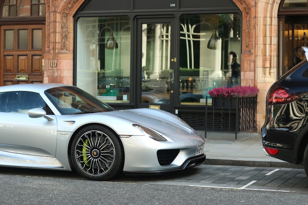 a silver sports car parked next to a black car