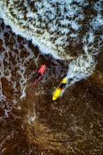 a couple of people riding on top of surfboards in the ocean
