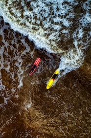 a couple of people riding on top of surfboards in the ocean