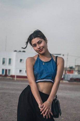 A model wearing a casual chic dress, smiling in an outdoor urban setting.