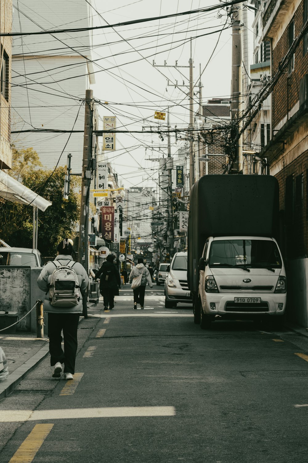 a group of people walking down a street next to tall buildings