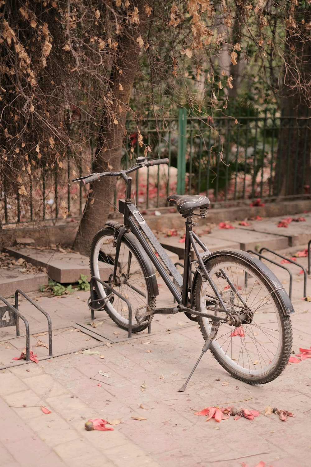 a bicycle parked on a sidewalk next to a fence