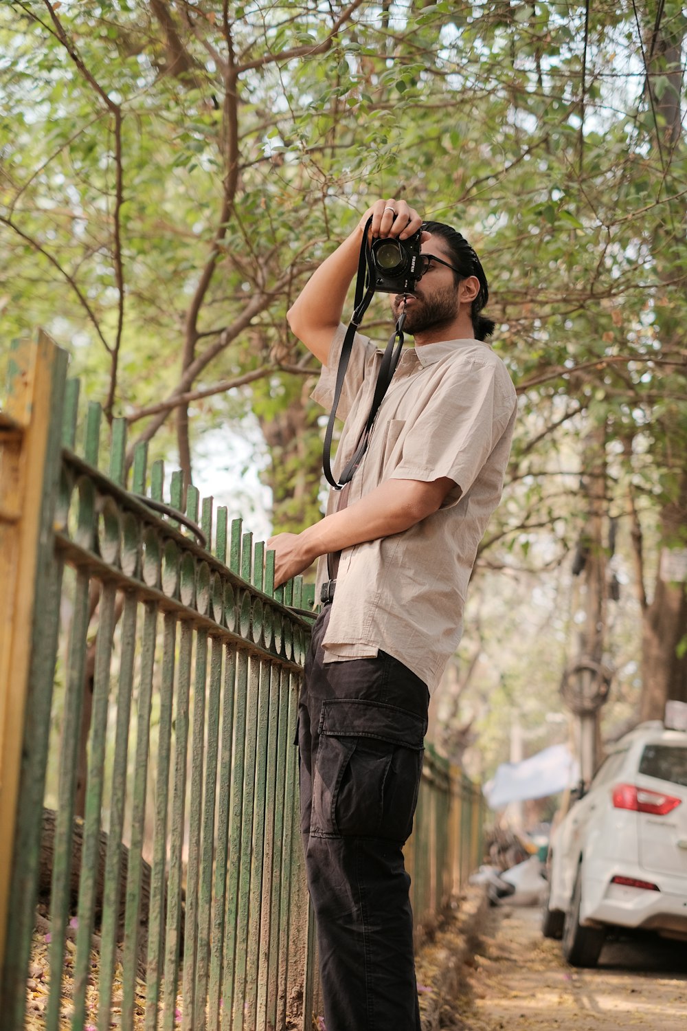 a man standing next to a fence holding a camera