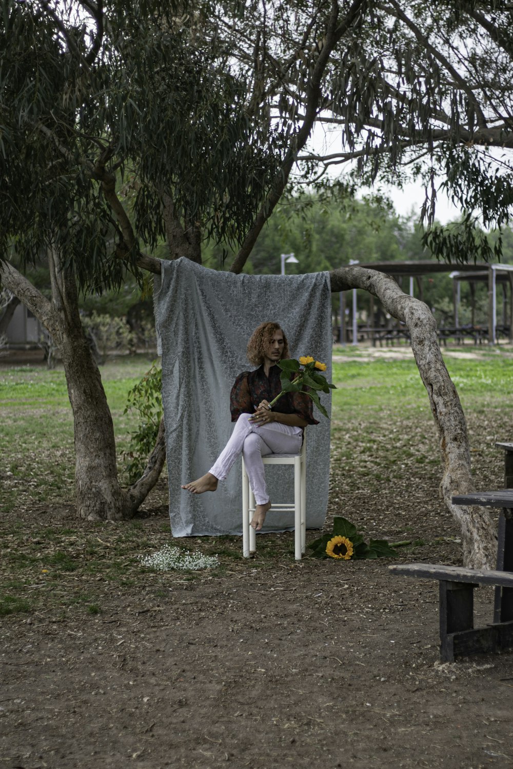 a woman sitting in a chair under a tree