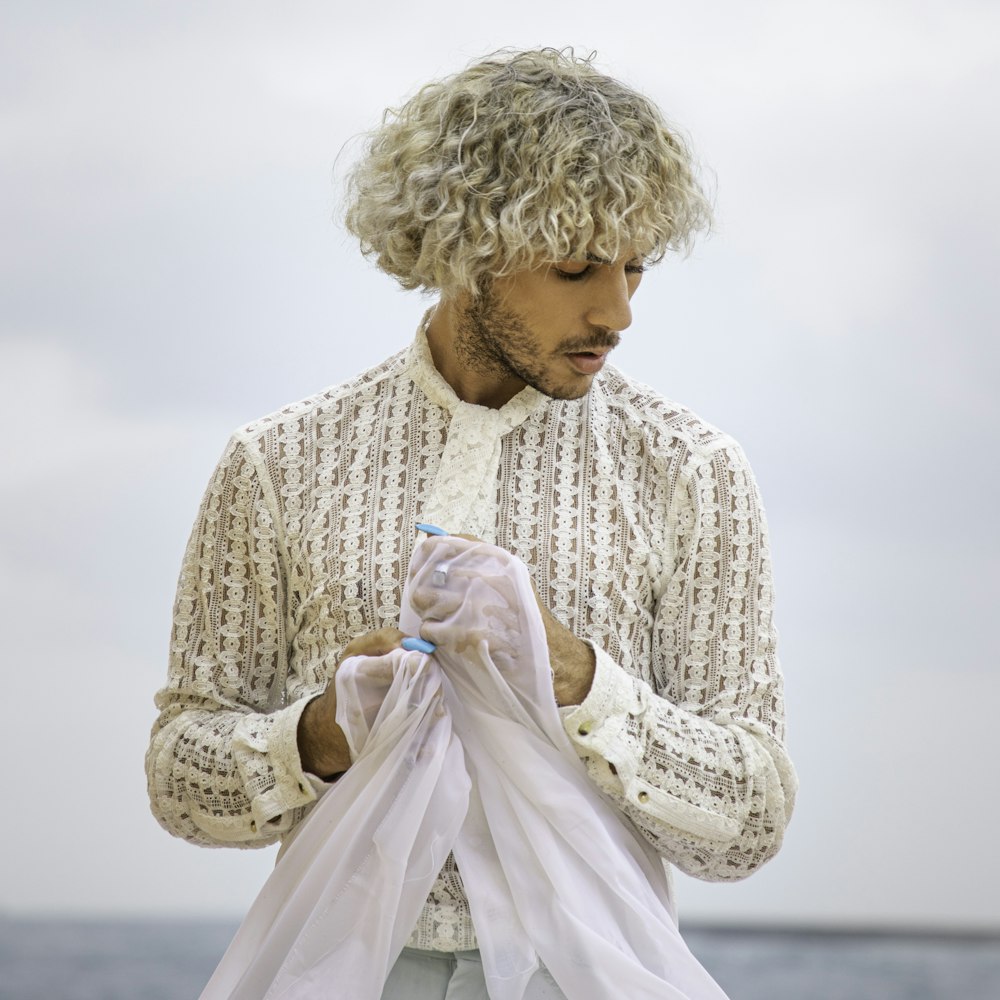 a man with curly hair holding a white shirt