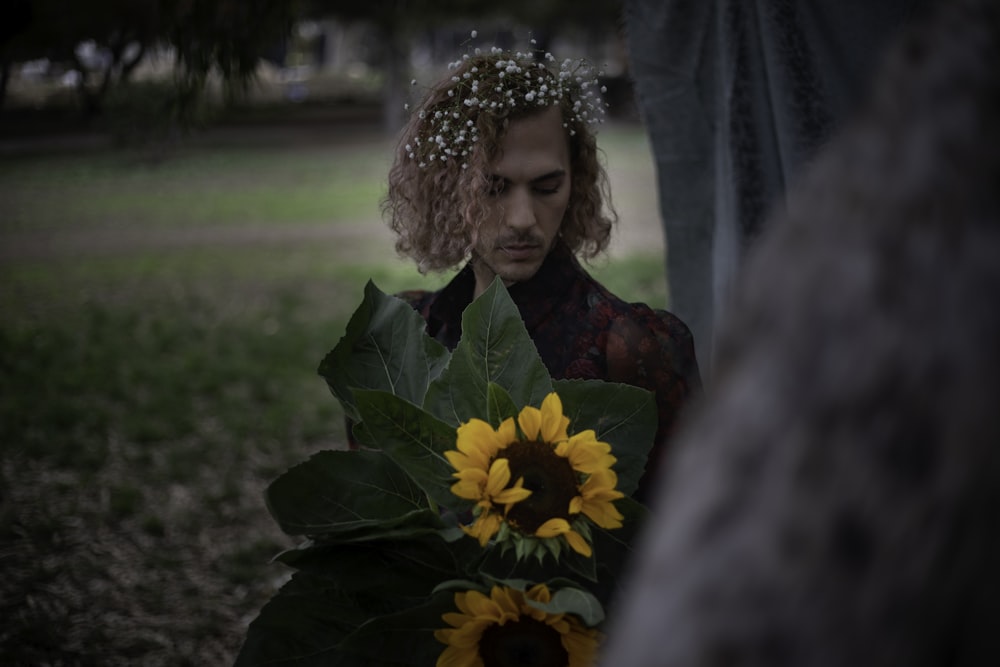 a woman holding a bouquet of sunflowers in a park