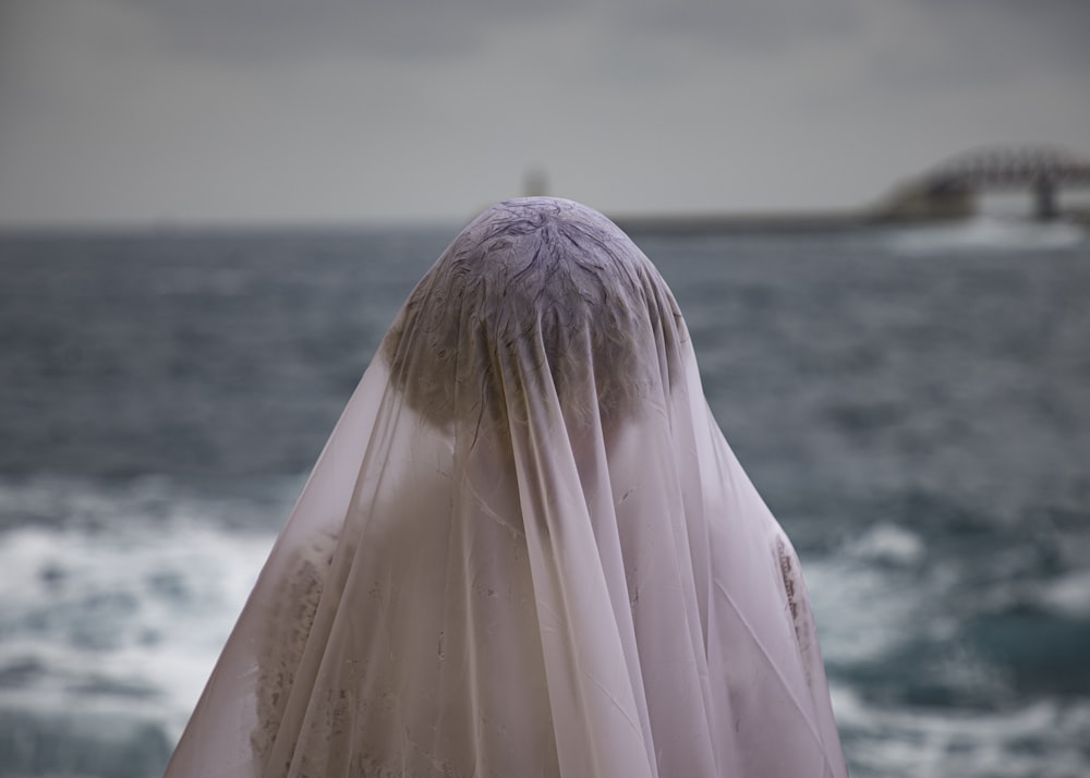 a woman wearing a veil standing on a beach