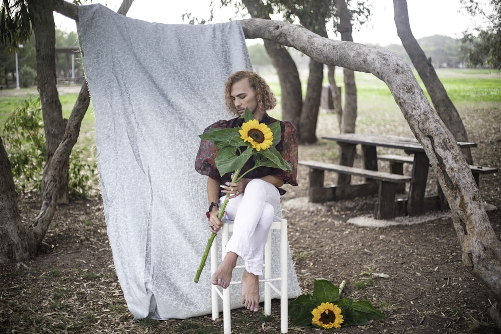 a woman sitting on a chair holding a bouquet of sunflowers