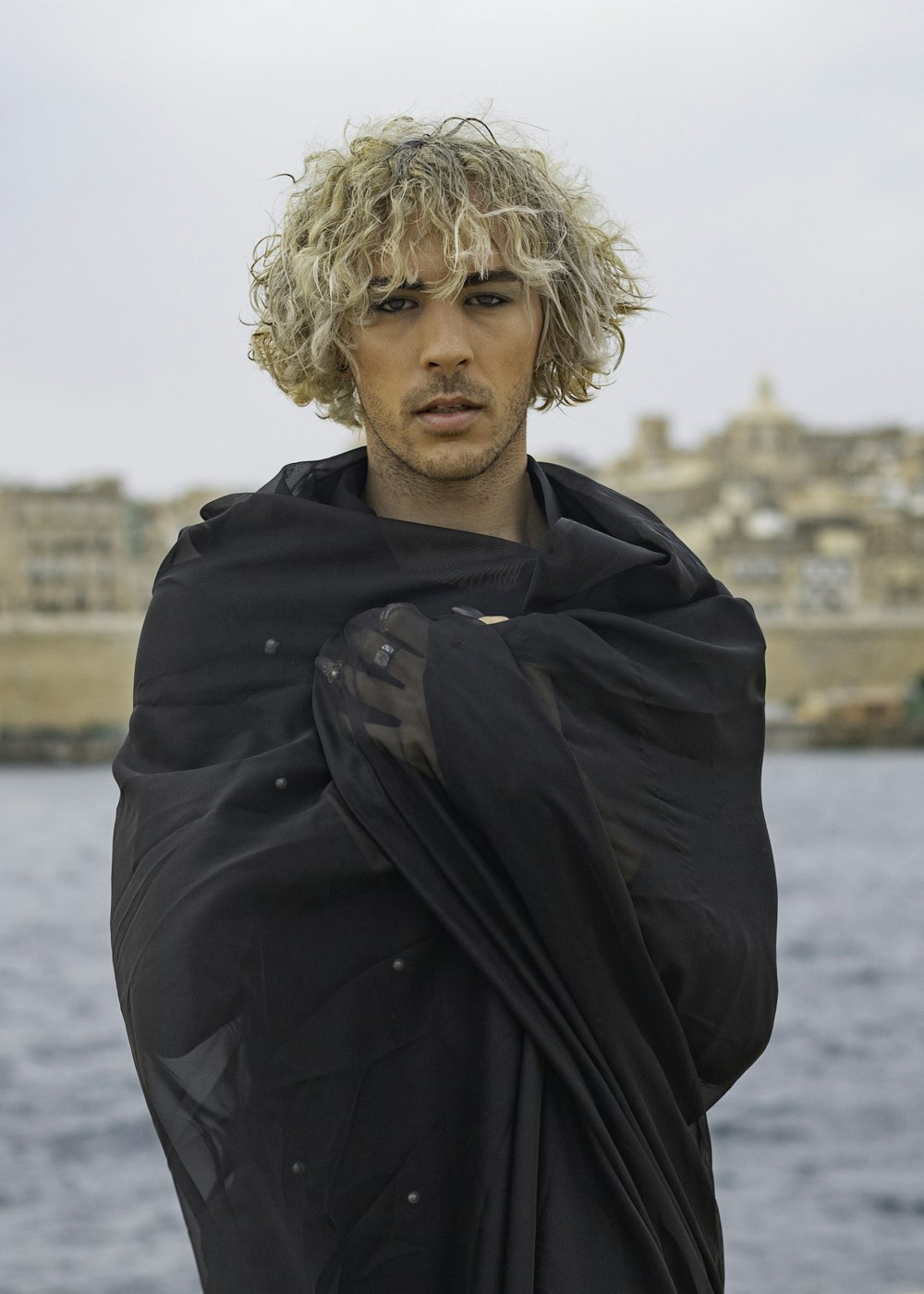 a man with blonde hair wearing a black shawl