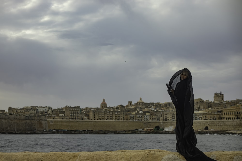 a woman is standing on a rock by the water