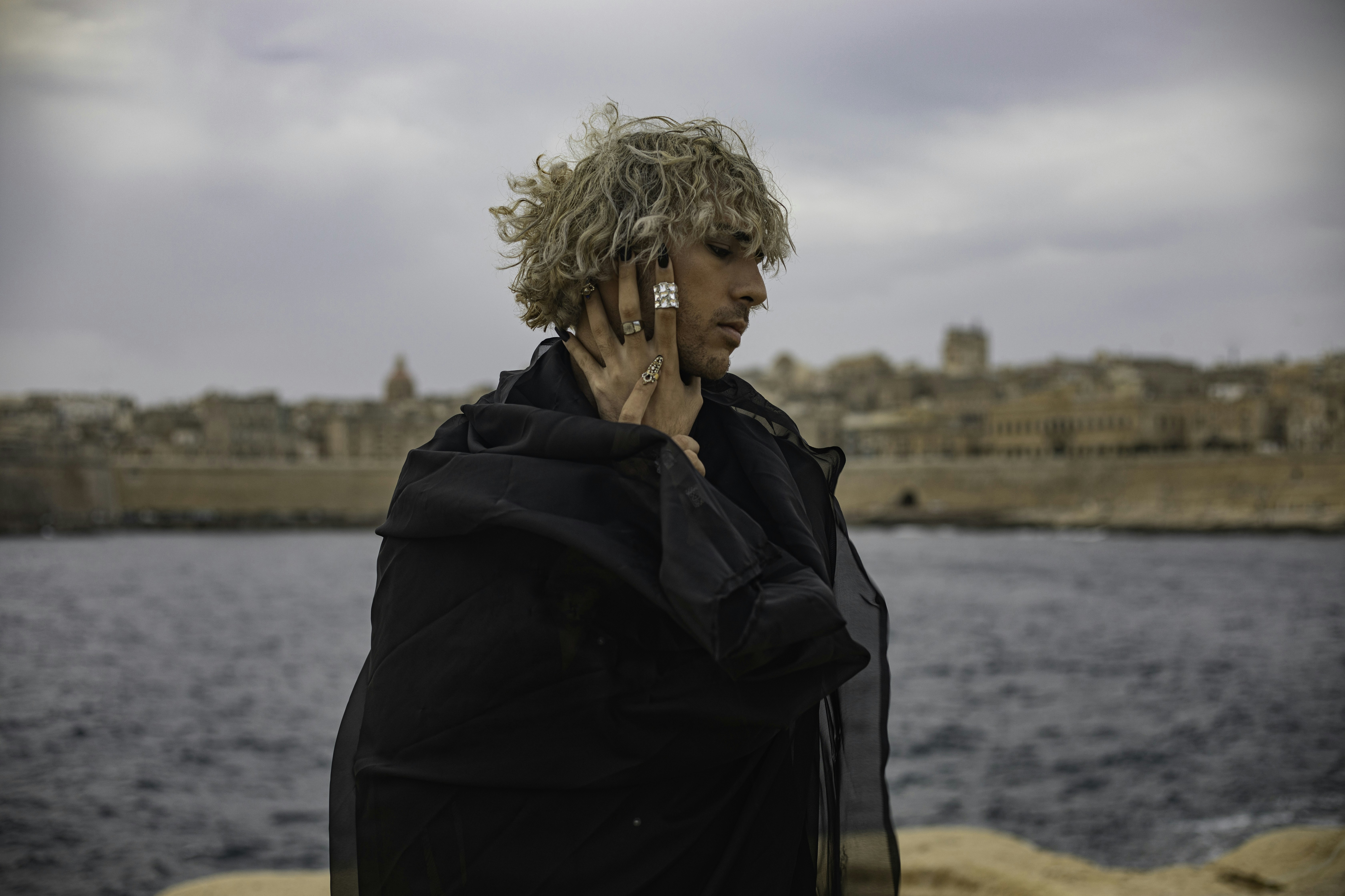 a man talking on a cell phone next to a body of water
