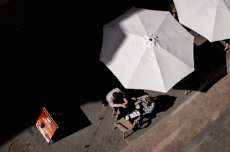 an overhead view of two people sitting at a table with umbrellas