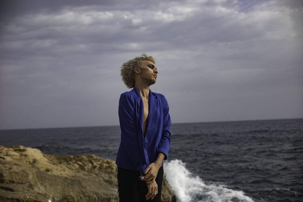 a woman standing on a rock near the ocean