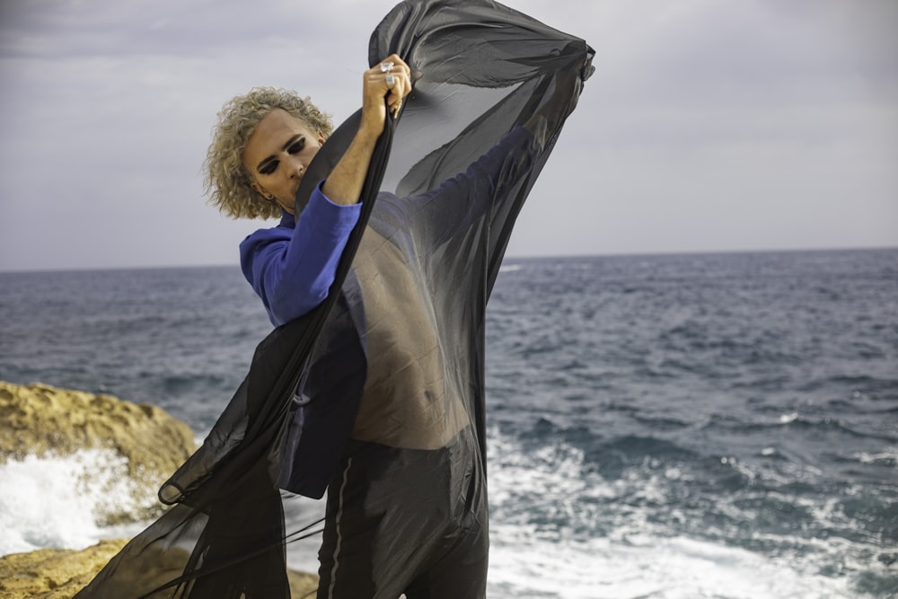 a woman standing on a beach holding a scarf