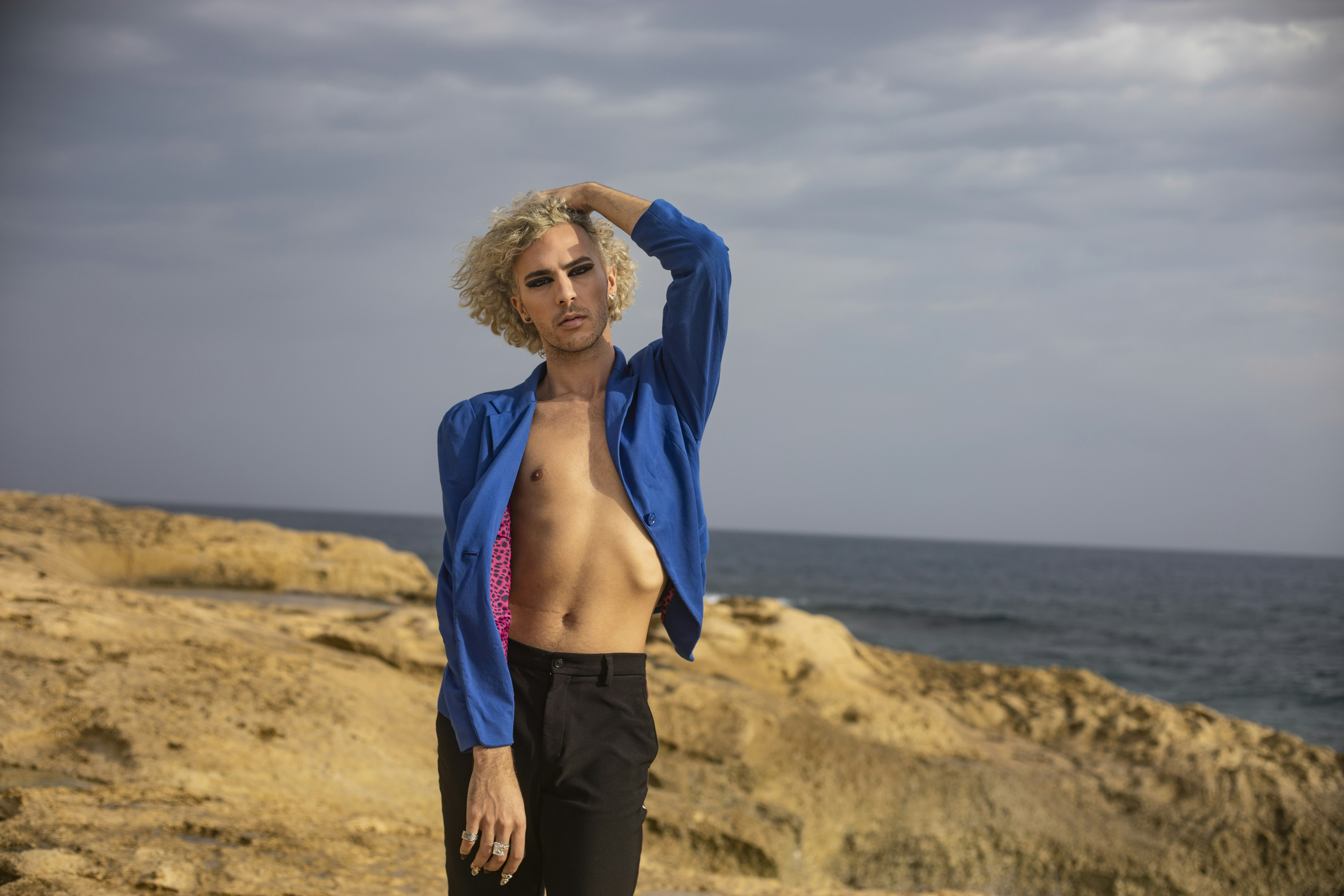 a shirtless man standing on a rocky beach next to the ocean