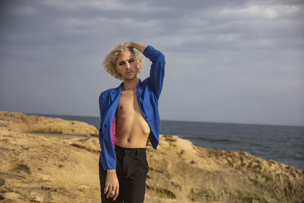 Happy client posing in front of a cloudy blue sky beach scene, showing off her transformation.