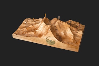 A layered wooden 3D topographical art piece of a ski hill with snow-covered peaks.