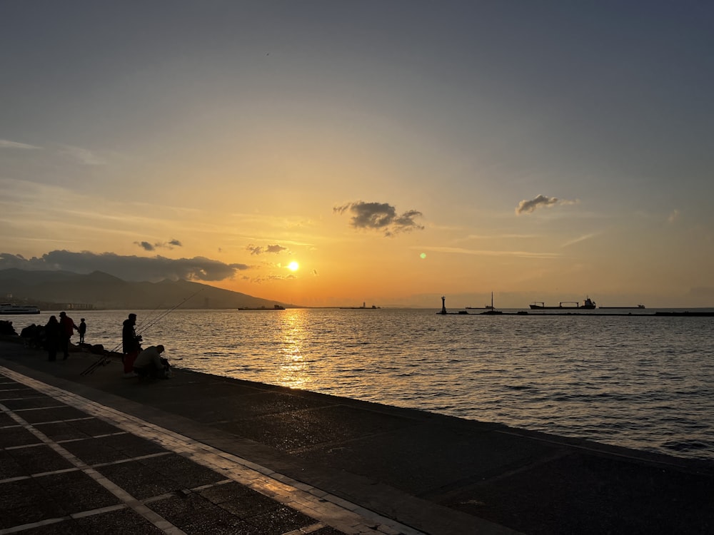 a group of people sitting on a pier watching the sun set