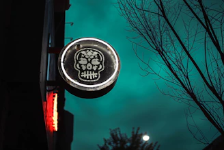 Bar decorated for Día de Muertos with colorful Mexican skull stickers on the walls.