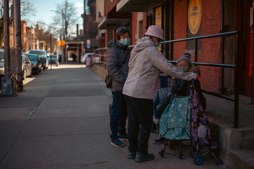 a group of people standing on a sidewalk next to a building