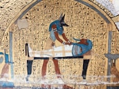 An ancient Egyptian art piece depicting Anubis, the jackal-headed god, performing a ritual on a mummified figure. Hieroglyphics fill the background, adding to the historical and cultural context.
