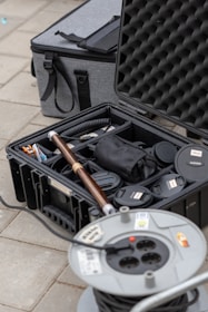 a black case filled with items sitting on top of a tiled floor