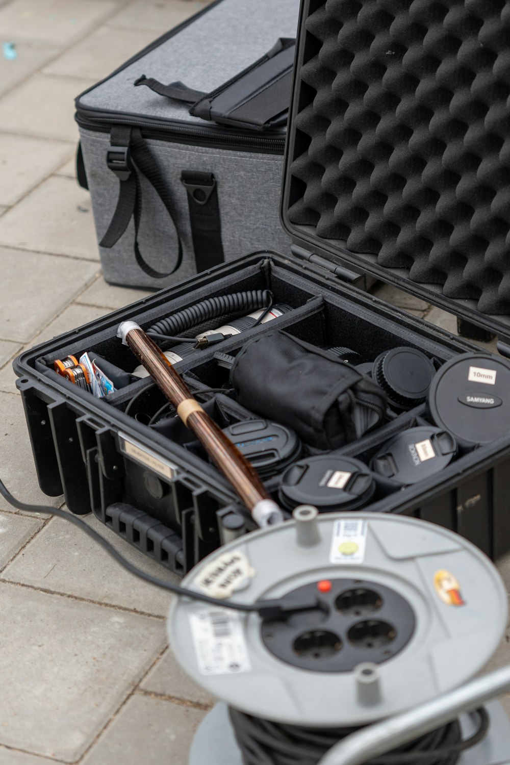 ein schwarzer Koffer gefüllt mit Gegenständen, die auf einem Fliesenboden sitzen