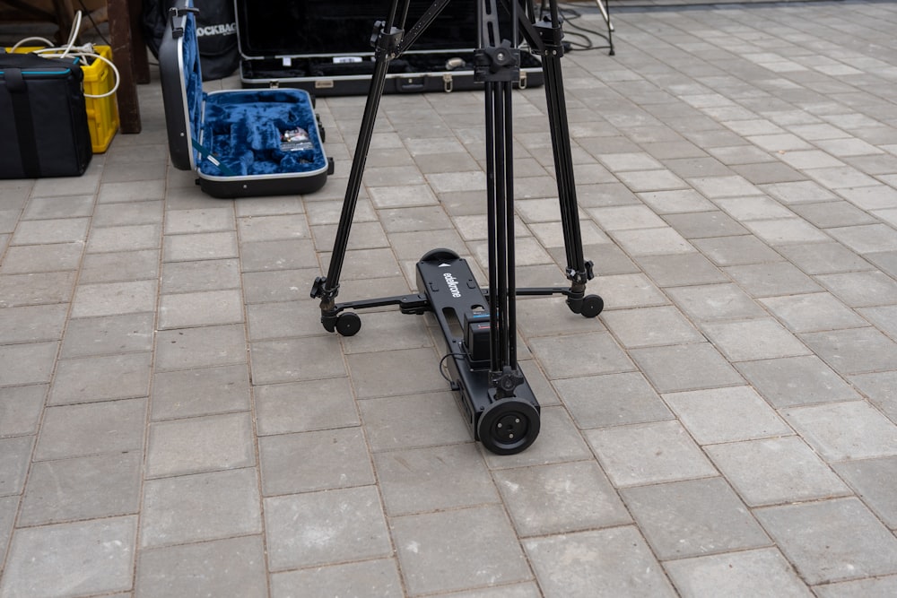 a tripod sitting on the ground next to a guitar case