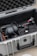 A protective case is open to reveal various audio-visual equipment inside. It includes headphones, a gimbal, and other accessories arranged neatly. The interior of the case is lined with foam padding for protection.