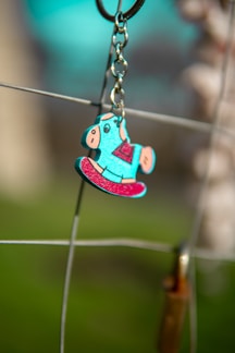 Close-up of a colorful acrylic keychain with a playful design hanging from a backpack zipper.