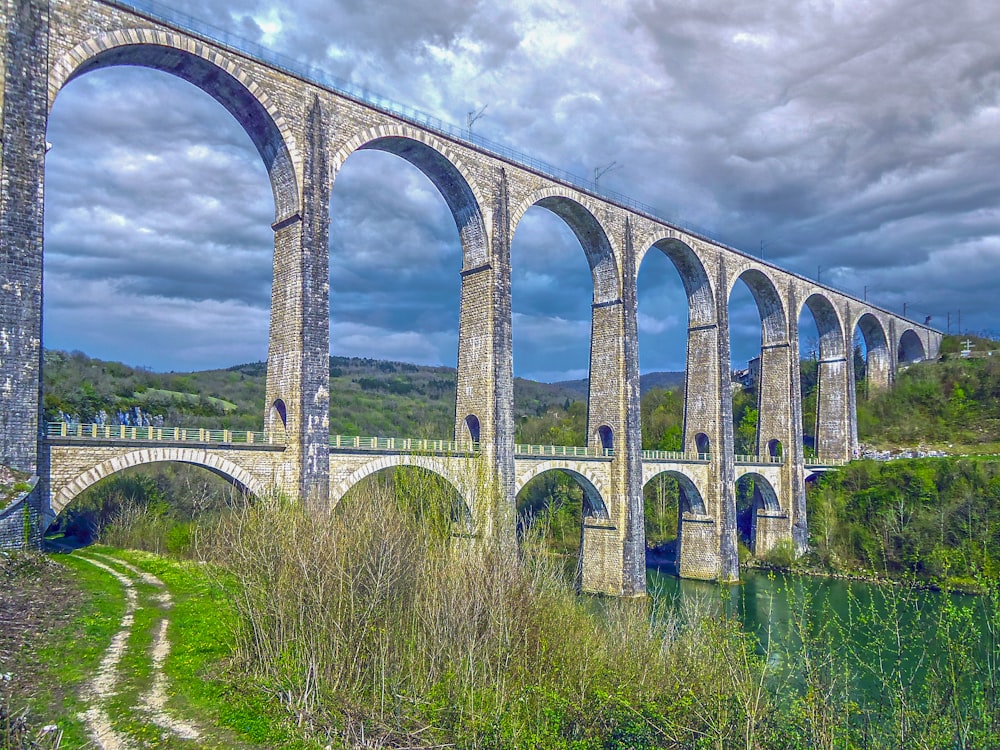 uma grande ponte de pedra sobre um rio sob um céu nublado