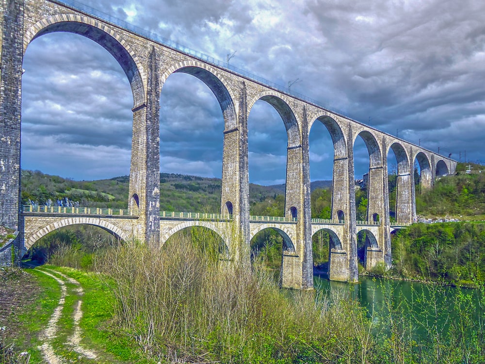 a large stone bridge over a river under a cloudy sky
